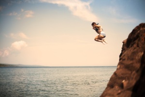Young Girl Jumping Off Cliff Into Water